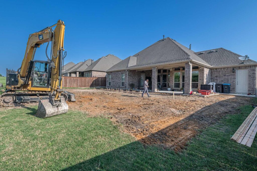 Excavator preparing a residential yard for septic drain field replacement