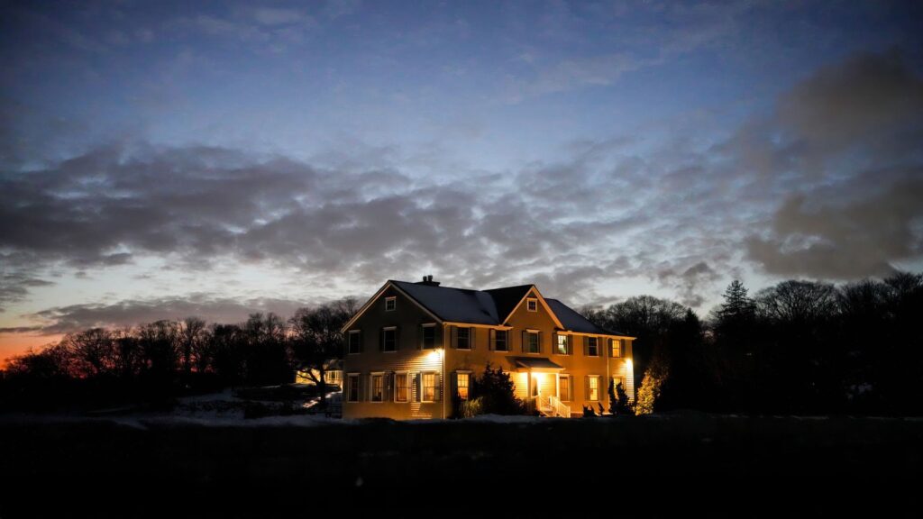 Rural Iowa farmhouse lit up at dusk, representing an after-hours septic emergency call